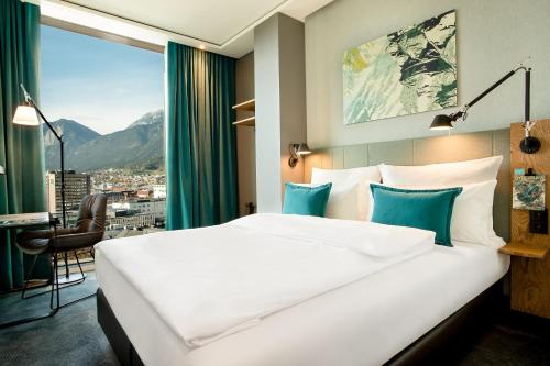 a hotel room with a large white bed and a window at Motel One Innsbruck in Innsbruck