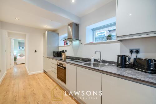 a kitchen with white cabinets and a wooden floor at 2BR House, Walk to Windsor Castle, Parking for 2 in Windsor
