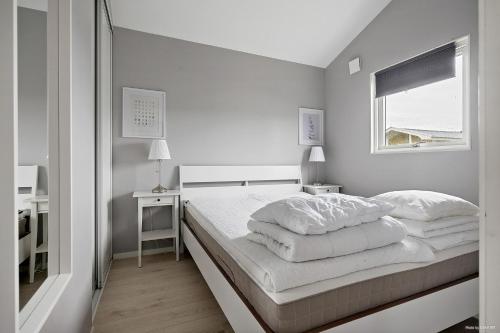 a white bedroom with a bed and a window at First Camp Vadstena - Vättern in Vadstena