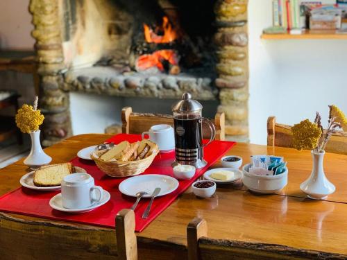 une table avec de la nourriture et du café sur une table avec une cheminée dans l'établissement ESTANCIA LA SERENA, à Perito Moreno