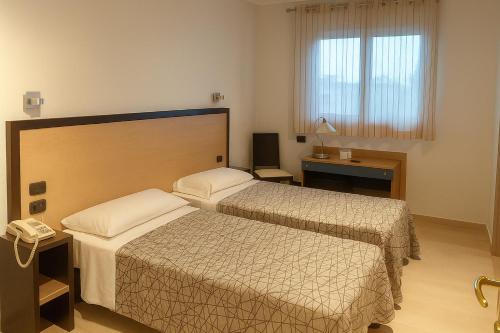 Una habitación de hotel con dos camas y un teléfono. en Hotiday Conegliano, en Conegliano