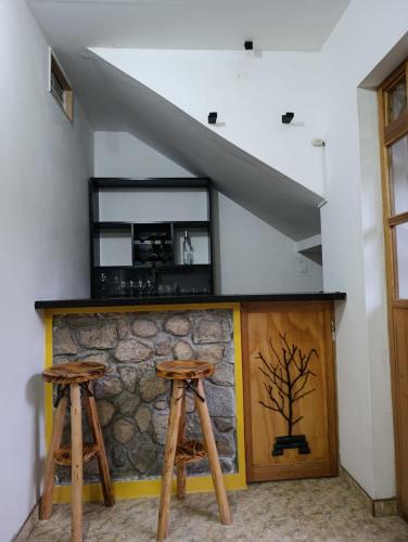 two wooden stools in front of a stone bar at Qushi Shoncu Lodge in Huaylas