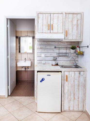 a kitchen with a white refrigerator and a sink at Harama Hotel Schinousa in Schinoussa