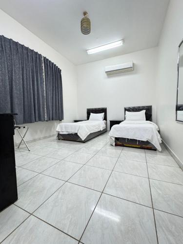 two beds in a room with a tiled floor at شقق طرابزون المخدومة in Rumāḩ