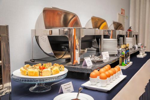a buffet line with cakes and eggs on a counter at VIP Executive Santa Iria Hotel in Santa Iria da Azóia