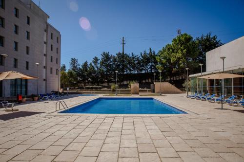 a swimming pool in a courtyard next to a building at VIP Executive Santa Iria Hotel in Santa Iria da Azóia