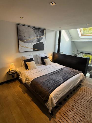 a bedroom with a large bed with a painting on the wall at Maison d'hôte Yourehome 2 belles chambres à louer individuellement dans un écrin de verdure in La Hulpe