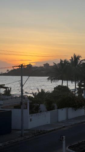 a sunset over the ocean with palm trees and a street at Orla Pousada & Café in Parnamirim