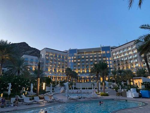 a large hotel with a swimming pool in front of a building at 3 Bedroom Suite Building-Wide Balcony Fujairah in Fujairah