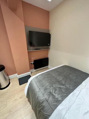 a bedroom with a bed and a flat screen tv at Modern Studio Bolton ,Free Parking, Fast WiFi, Ideal for Contractors & Long Stays in Bolton