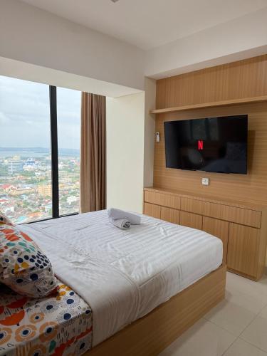 Un dormitorio con una cama y un televisor de pantalla plana. en Modern 1BR with City & Sea View, en Batam Centre
