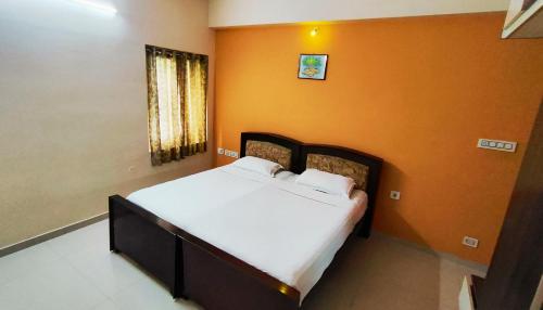 a bed in a room with an orange wall at RBS NEST in Tiruchchirāppalli