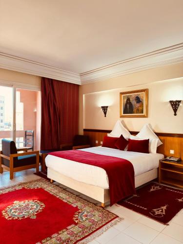 a bedroom with a large bed and a red rug at Hotel Idou Tiznit in Tiznit