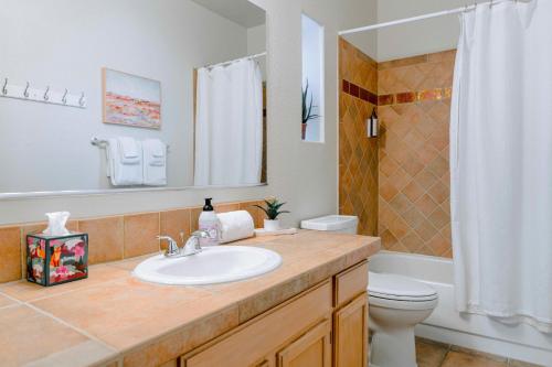 een badkamer met een wastafel, een toilet en een spiegel bij Canyon Crest Condo in Tucson