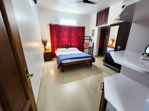 een slaapkamer met een bed en een rood gordijn bij Shebin's Home Stay Thiruvalla in Thiruvalla