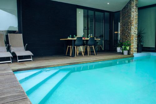 a swimming pool with a table and chairs in a house at Portugal Alma - Oporto Guesthouse - Private Heated Pool in Ermesinde