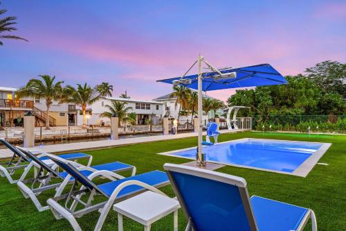a pool with chairs and an umbrella in a yard at Surfstream Edge in Marathon Airport