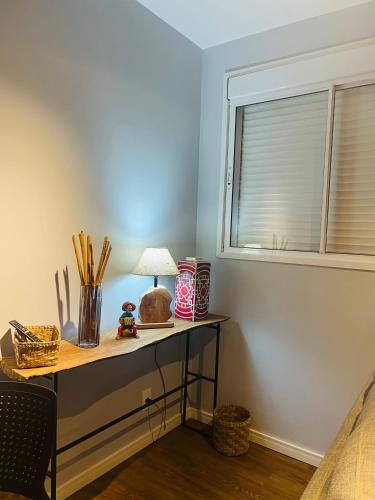 a desk with a lamp on it next to a window at Allianz Vila Romana in São Paulo