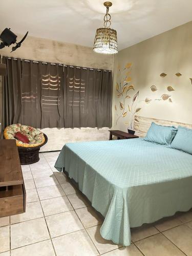 a bedroom with a blue bed and a chair at Recanto do Amor in Cascavel