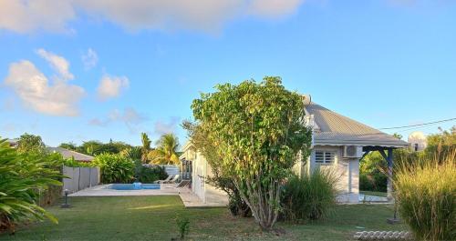 ein Haus mit einem Garten mit einem Baum in der Unterkunft Villa Blue Sky in Saint-François