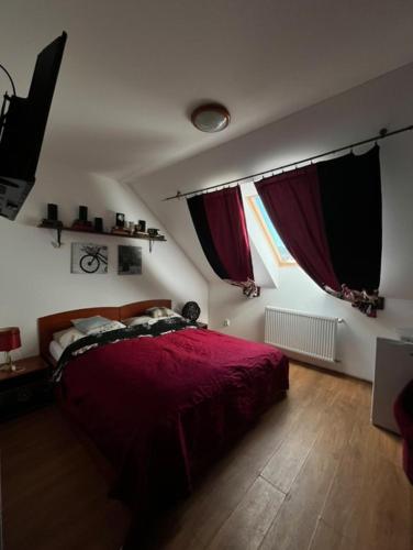 een slaapkamer met een rood bed en 2 ramen bij Penzión Korytnačka in Námestovo