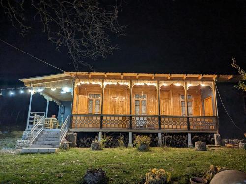a wooden house with a porch at night at Kipiani guest house ყიფიანის სახლი in Khvanchkara