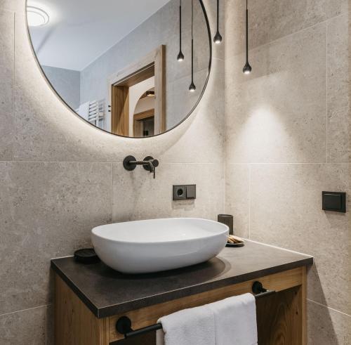 a bathroom with a large white sink and a mirror at Miraval Perathoner Andreas in Ortisei