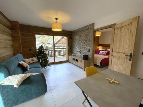 a living room with a blue couch and a bedroom at Appartement Haut de Gamme neuf avec deux terrasses - 6 personnes - App 102 in Saint-Sorlin-dʼArves