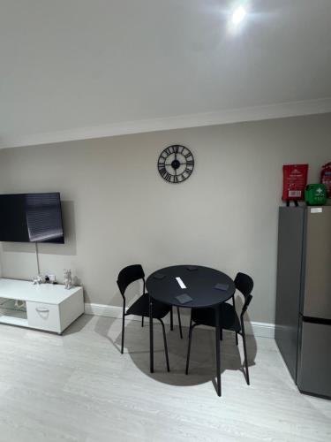 a table and chairs in a kitchen with a clock on the wall at Modern Studio Apartment Shoreditch in London