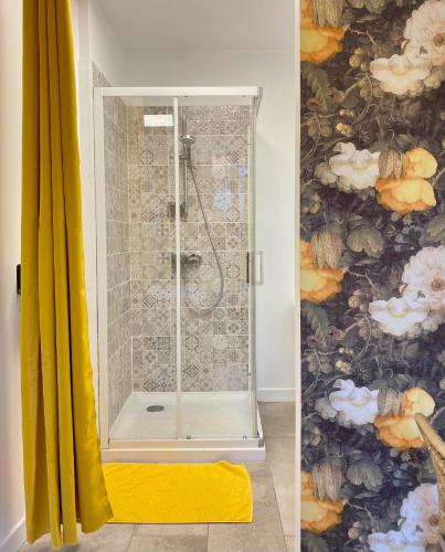 a shower with a glass door next to a yellow shower curtain at Médiévale 27 in Semur-en-Auxois