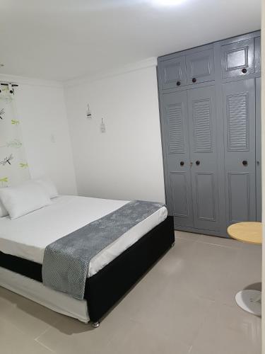 a white bedroom with a bed and a table at Apto San José in Armenia