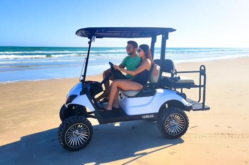 Ein Mann und eine Frau sitzen in einem Golfwagen am Strand in der Unterkunft Golf Cart - Walk to Beach - Pool - Pets - Floor BR in Port Aransas
