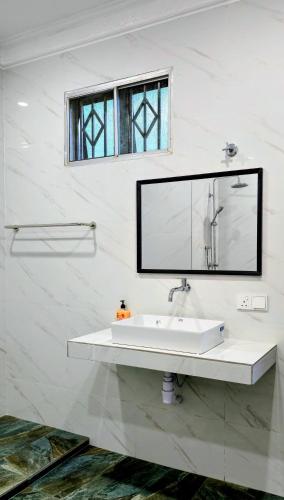a white bathroom with a sink and a mirror at Gasing WheelHouse in Petaling Jaya