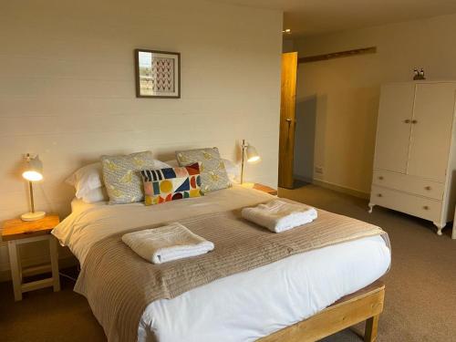 une chambre avec un grand lit avec deux serviettes dessus dans l'établissement Mick's Cottage, à Crail