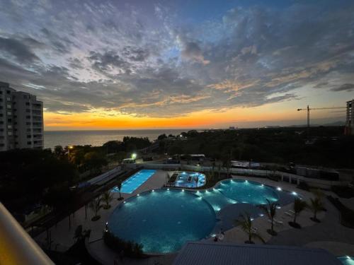 a view of a swimming pool at sunset at Apartamento con vista,piscina y playa -SantaMarina-803 in Santa Marta