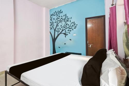 a bedroom with a bed with a tree painted on the wall at SPOT ON Gorav Smark in Malhour