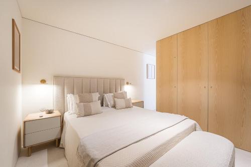 a white bedroom with a large bed and a cabinet at DPV Residences - Studio CA/C1 in Porto