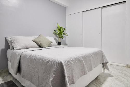 una camera da letto bianca con un letto con una pianta sopra di La Reserve a Porlamar