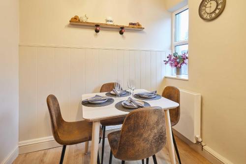 een eettafel met stoelen en een klok aan de muur bij Host & Stay - Daisy Cottage in Masham