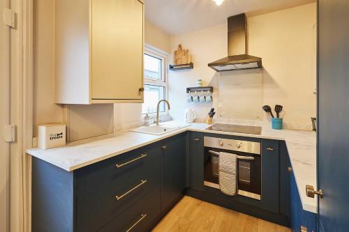 een keuken met blauwe kasten en een wastafel bij Host & Stay - Daisy Cottage in Masham