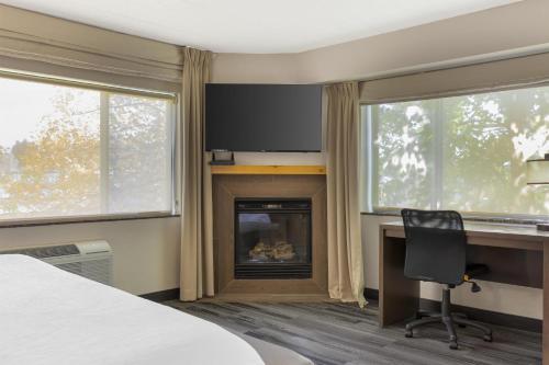 a bedroom with a fireplace and a desk and a chair at Best Western Plus McCall Lodge and Suites in McCall
