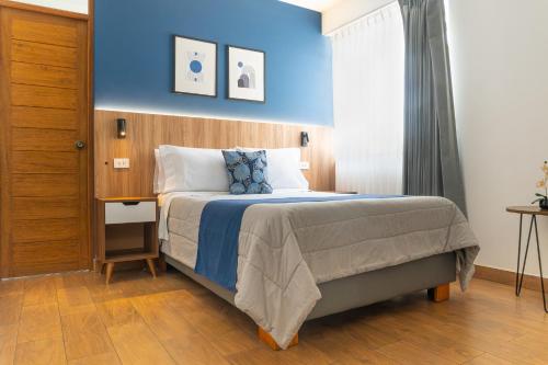 a bedroom with a bed with a blue wall at Majhu Hostal in Tacna