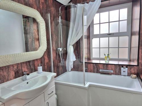 een badkamer met een bad, een wastafel en een spiegel bij Winster Cottage, Meathop, Grange-Over-Sands in Grange Over Sands