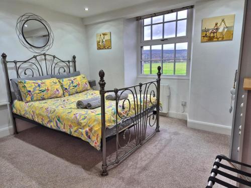 een slaapkamer met een bed, een spiegel en een raam bij Winster Cottage, Meathop, Grange-Over-Sands in Grange Over Sands