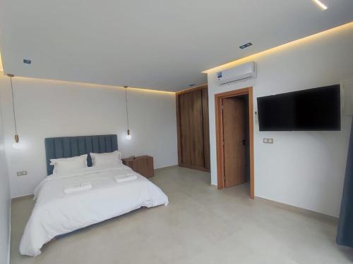 Un dormitorio con una cama y un televisor de pantalla plana. en Casa del mar, en Agadir nʼ Aït Sa