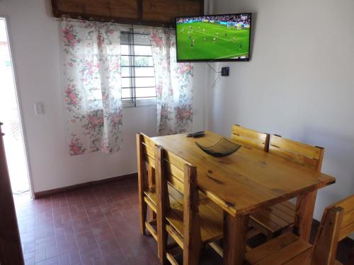 a dining room with a wooden table and a tv on the wall at El descanso in Las Toninas