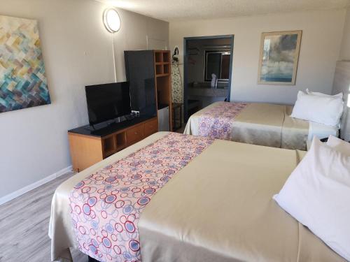 ein Hotelzimmer mit zwei Betten und einem Flachbildfernseher in der Unterkunft Discovery Inn Lafayette in Lafayette