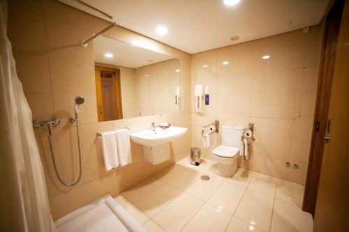 a bathroom with a sink and a toilet and a shower at Hotel Bagoeira in Barcelos