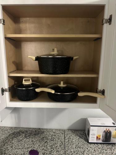 a cupboard with three pots and pans in it at Guest house 7 mins From stadium in Opa-locka