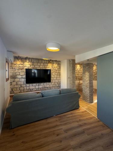 a living room with a couch and a tv on a brick wall at לוריא יוקרה בעתיקה in Safed